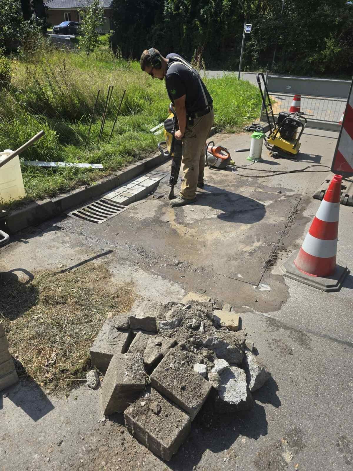 Mitarbeiter bricht mit einem Presslufthammer den Asphalt