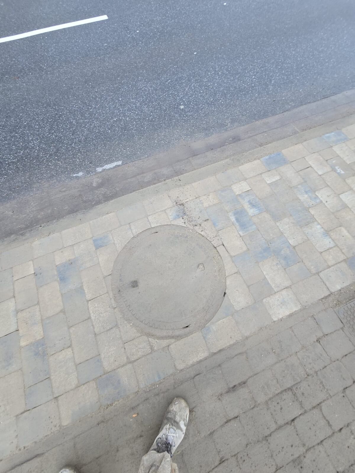 Pflasterarbeiten und ein Gulli an einer Straße